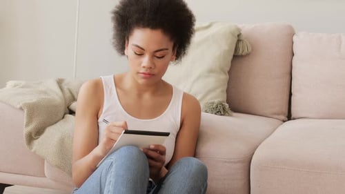 Woman Thinking and Writing in a Notepad at Home