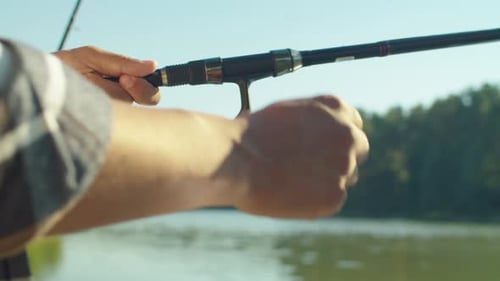 Nahaufnahme eines schwarzen Fischers mit Angelrute und Drehrolle am See