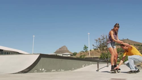 Woman Learning to Skateboard with Man's Help