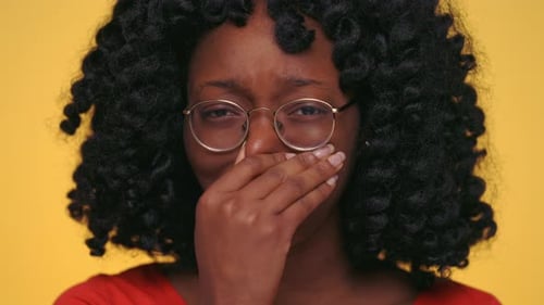 Woman Covering Mouth Against Yellow Background