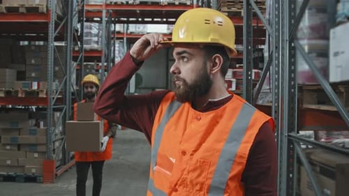 Männlicher Lagerarbeiter setzt Schutzhelm auf