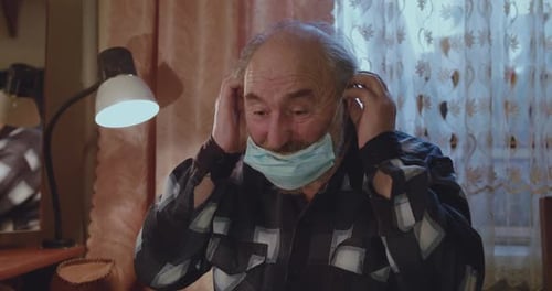 Senior Man Puts on Protective Surgical Mask