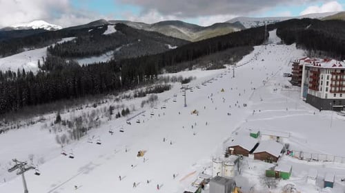 Vue aérienne d'un grand nombre de personnes skiant sur les pistes de ski près des remontées mécaniques de la station de ski