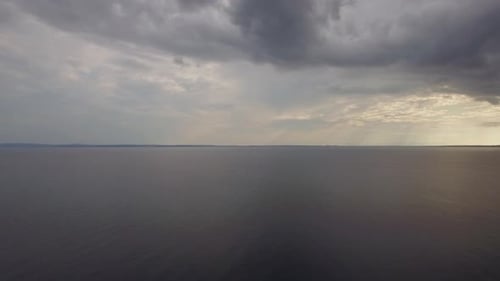 Aerial view of quiet sea, grey clouds in evening sky