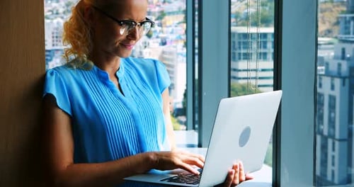 Smiling Woman Working on Laptop in Modern Office