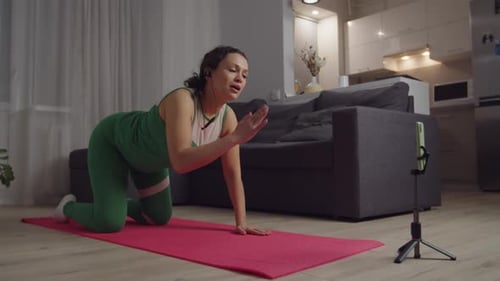 Entrenadora femenina sostiene un tutorial en línea en vídeo que muestra el ejercicio de un gato y una vaca