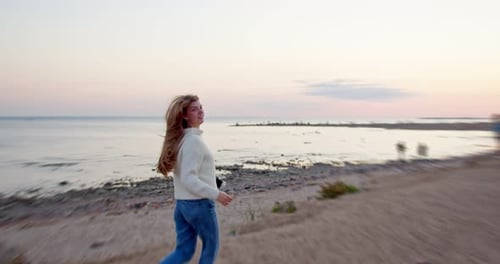 Woman with Prosthetic Arm Walks on Beach at Sunset
