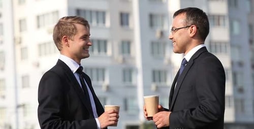 Businessmen Talking and Holding Coffee Cups Outdoors