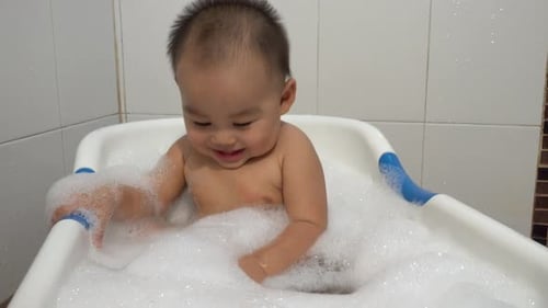 Happy Baby Playing in a Bubbly Bath