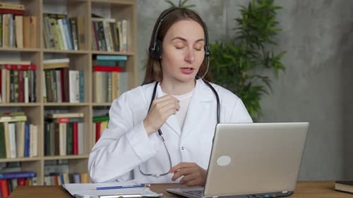 Woman Doctor Consults Online Using Laptop and Headset
