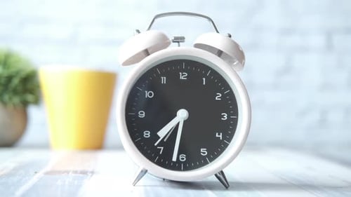 Alter Wecker und gelbe Kaffeetasse auf dem Tisch
