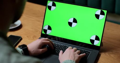 Close Up of Man Working on Laptop with Green Screen in Coffee Shop