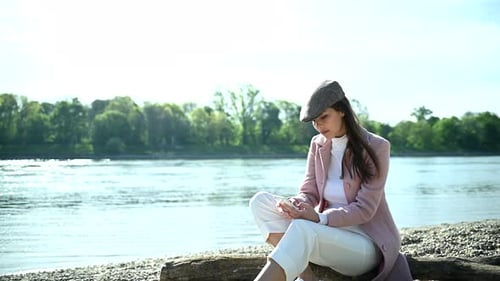 Stylish Woman Using Phone by River on Sunny Day