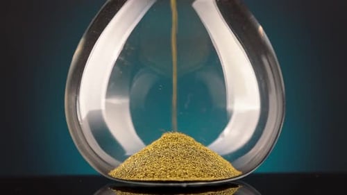 An Hourglass Made of Yellow Metal Shavings Passes Through a Funnel Symbolizing the Concept of Time