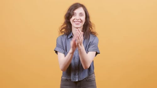 Woman Clapping Hands in Front of Orange Background