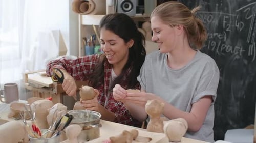 Two Young Women Crafting Plaster Figures Together