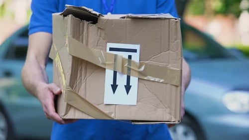 Delivery Man Holds Damaged Package in Urban Setting