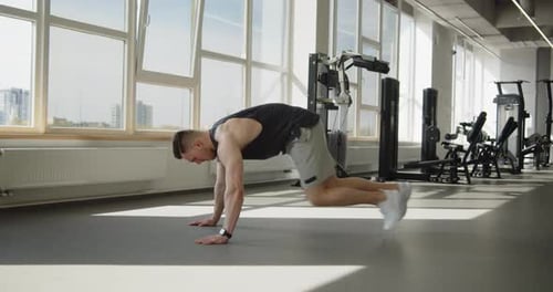 Young Muscular Athlete Works Out in Modern Gym Making Mountain Climbers Exercise