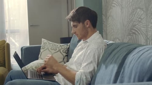 Focused Man Looking Laptop Screen Indoors. Thoughtful Guy Working Computer Hotel