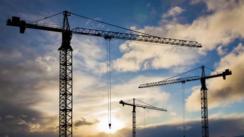 Construction Cranes Silhouetted Against Dynamic Sky