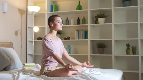 Woman Meditating on Bed in Lotus Position