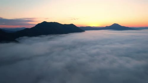 4K Scenic flight over beautiful mountain scape with bright sky and clouds