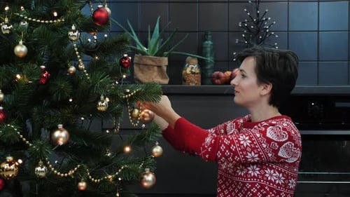 Woman Decorates Christmas Tree with Ornaments at Home