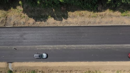 Top view of cars moving on new asphalt road. View from above on finished part of the road.