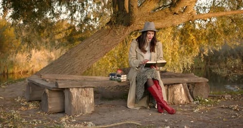 Woman Reading a Book on a Bench in Autumn