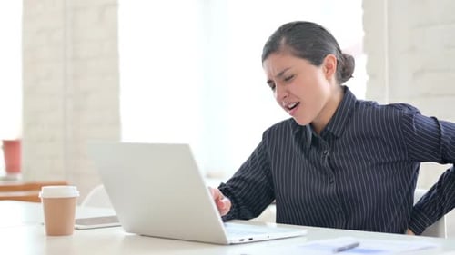 Woman Experiencing Back Pain While Working at Desk