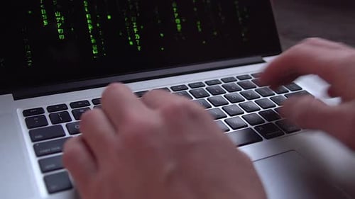 Close-up hacker hands typing on a laptop, The Matrix style binary code on laptop, falling number