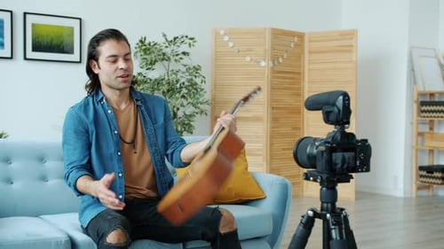 Man Playing Guitar and Recording Video at Home
