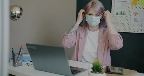 Portrait of Young Businesswoman Putting on Face Mask in Office During Covid19 Pandemic