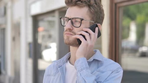 Lässiger junger Mann telefoniert im Freien