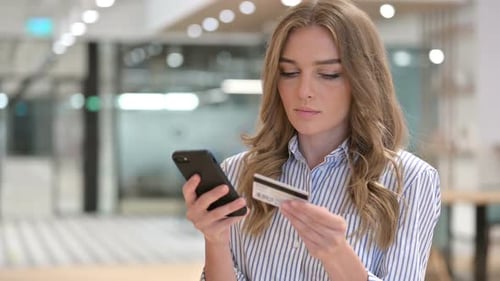 Woman Using Phone and Credit Card in Bright Office