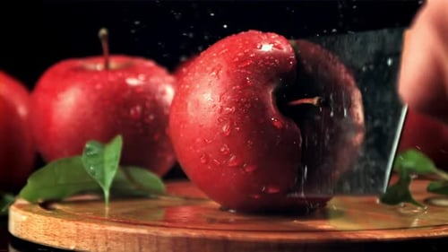 Ein reifer Apfel wird mit einem großen Messer in Hälften geschnitten