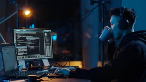Hacker in Headphones Using Laptop Computer at Nigt 7