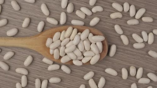 Wooden Spoon Holding White Beans on Wooden Surface