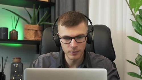 Man Working on Laptop Putting on Headphones