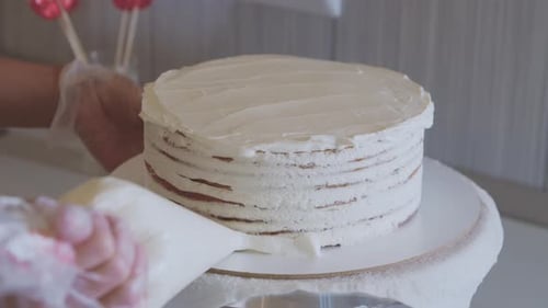 A Chef Covering Cake with White Vanilla Cream Using a Bakery Bag