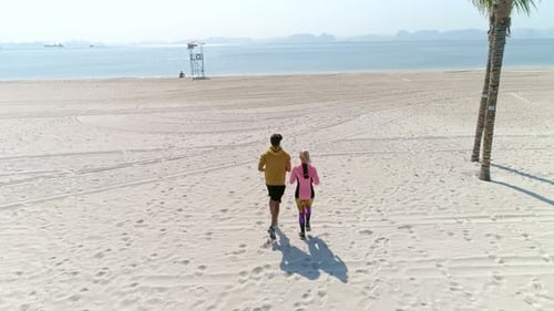 Drone view of woman running with partner. Shot with RED helium camera in 8K