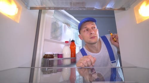 Repair Man Inspects the Refrigerator Interior