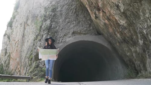 Woman Holding Map Stands at Tunnel Entrance