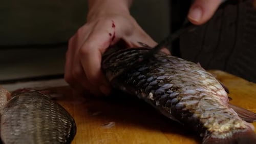 Scaling Fish with a Knife on Cutting Board