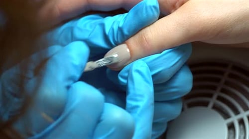 Close up footage of manicure artist making nail polishing with brush and tools