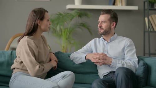 Pareja feliz conversando mientras está sentada en el sofá