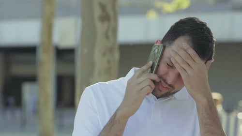 Upset Young Adult Man Talking on Phone Outdoors
