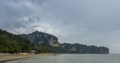 Zeitraffer von Regenwolken über Strand und Meereslandschaft mit Booten