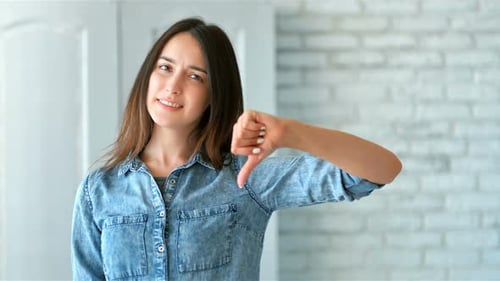 Young Woman Gives Thumbs Down Gesture Indoors