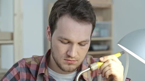 Young Man Concentrating on Precision Work at Table